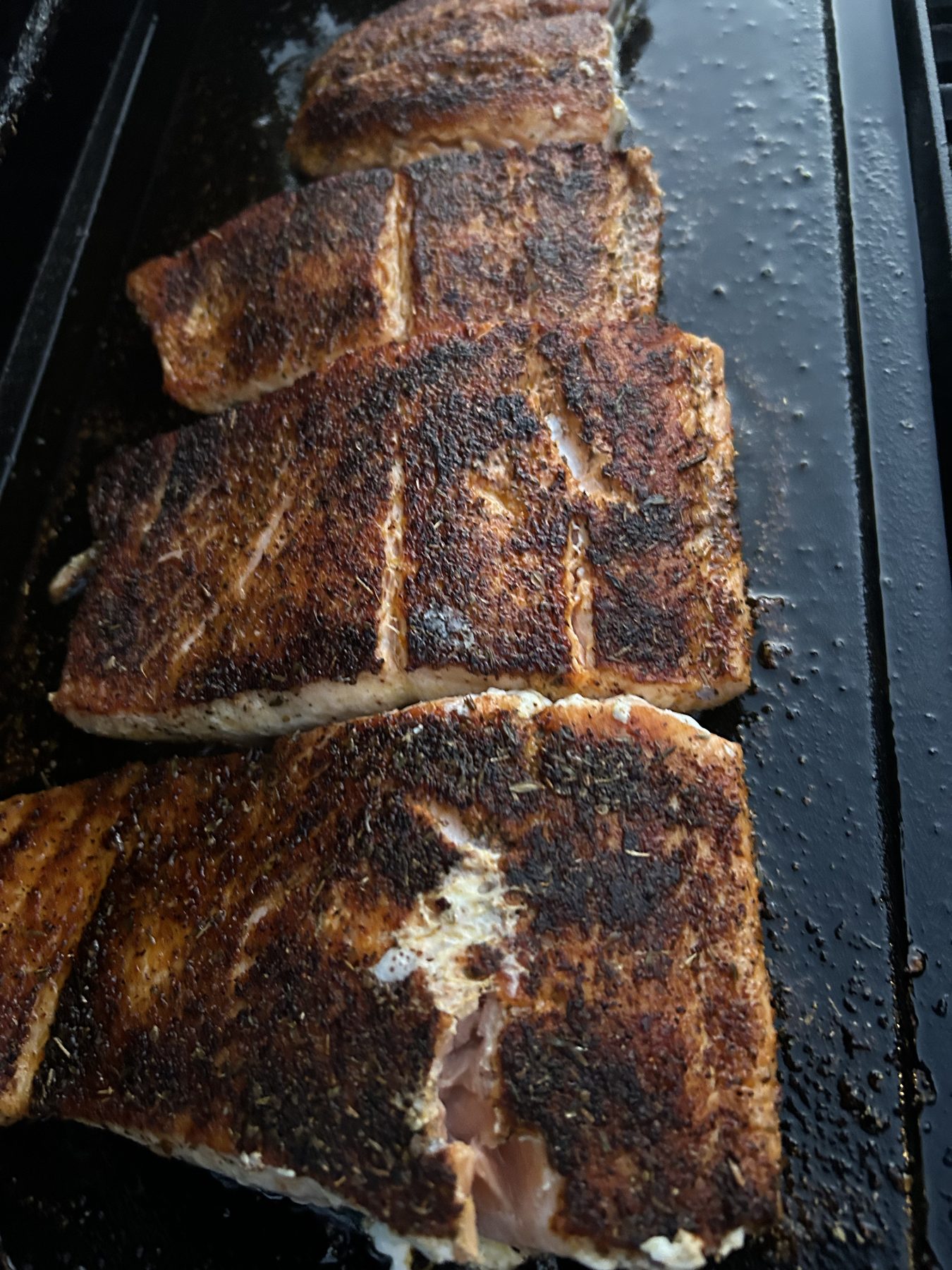 Blackened salmon after the first flip on a cast iron flat top