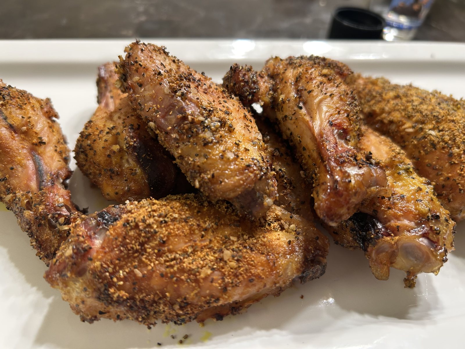 Finished lemon pepper chicken wings on a white platter