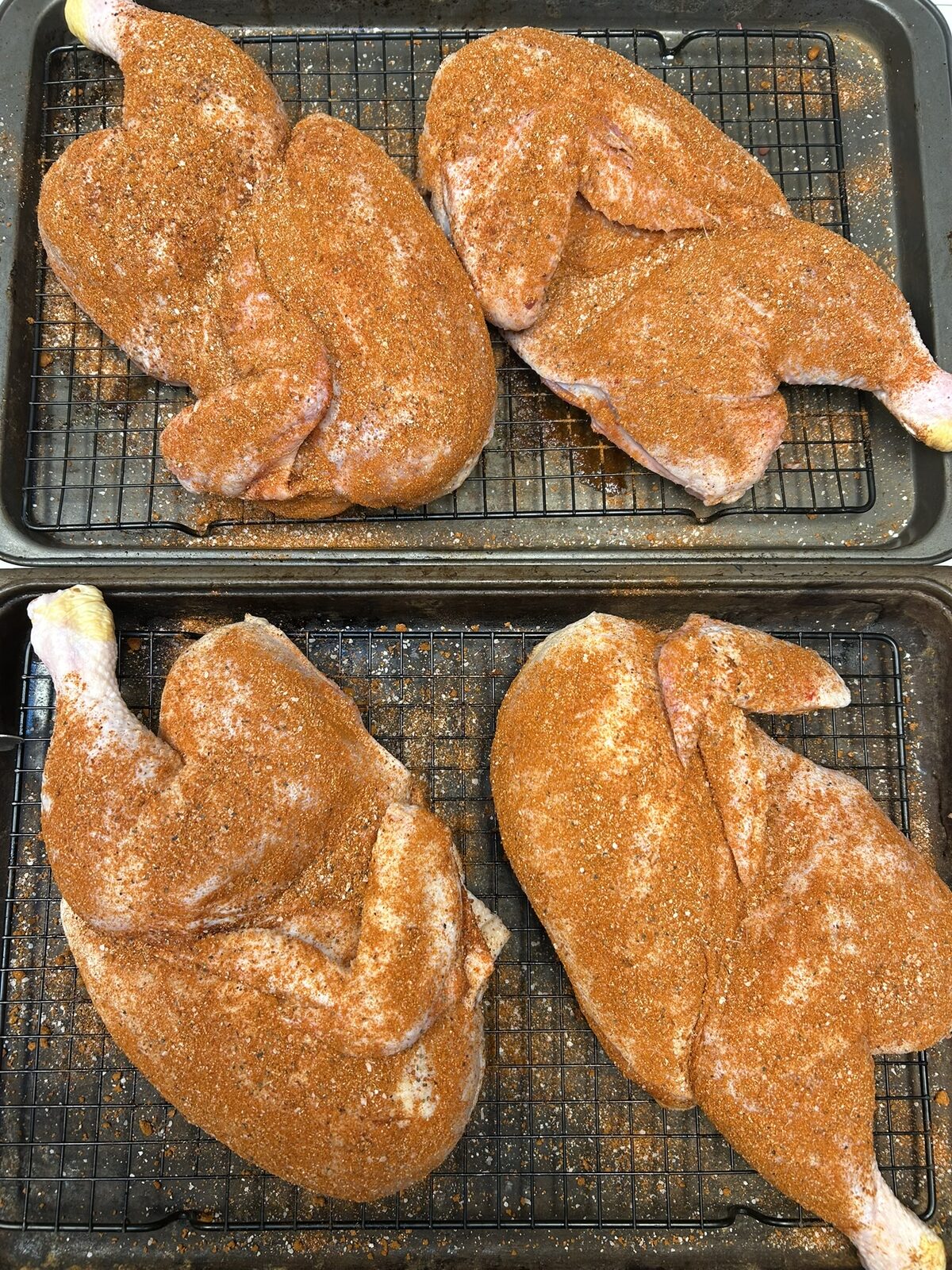 Half chickens rubbed with Nashville Hot Chicken Rub on a wire rack